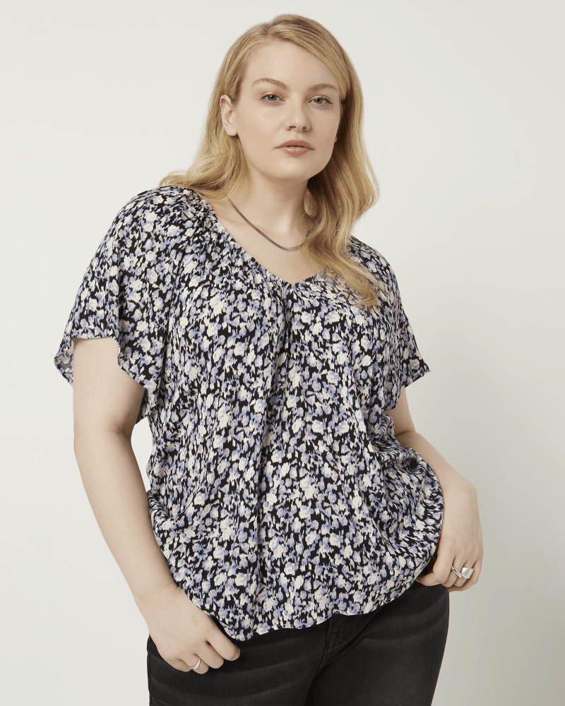 Front of a model wearing a size 1X Penny V-Neck Printed Top in Black / Purple by Bobeau. | dia_product_style_image_id:210513